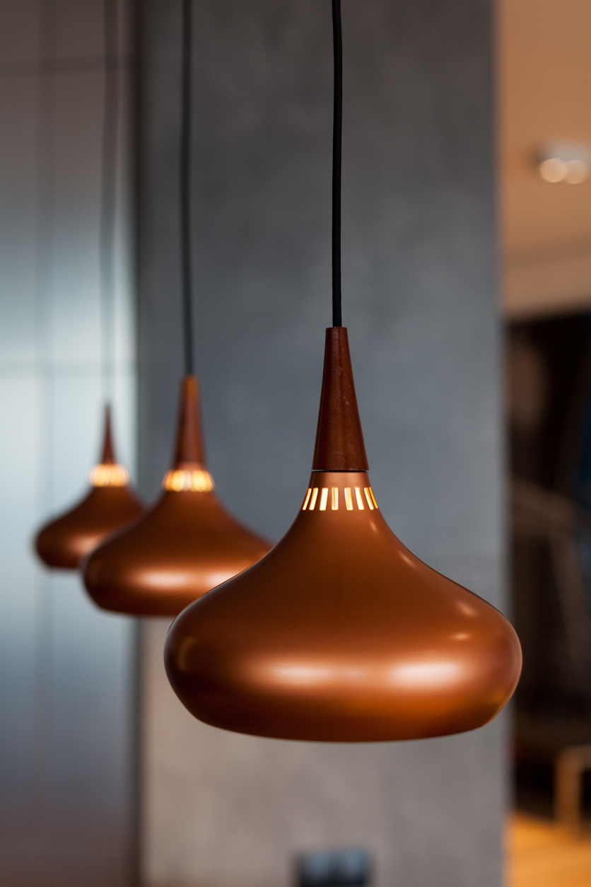 Three new lamps made of copper suspended from the ceiling in the dining room